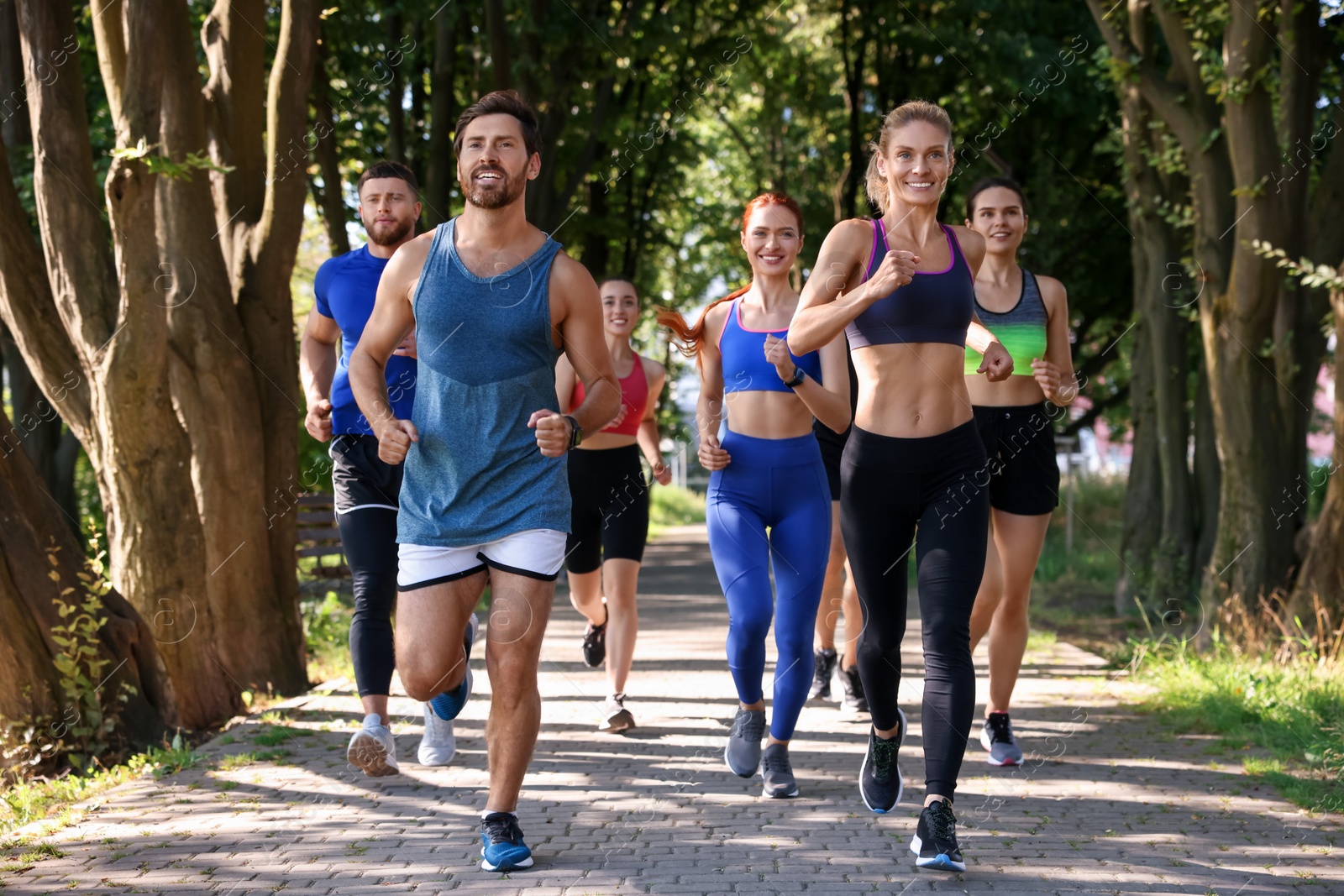 Photo of Group of people running in park on sunny day