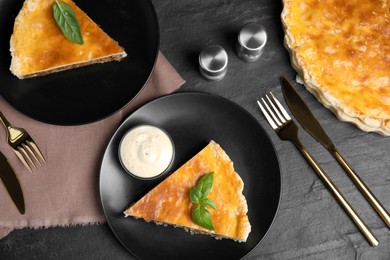 Delicious pie with minced meat, basil and sauce served on black table, flat lay