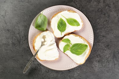 Photo of Delicious sandwiches with cream cheese and basil leaves on grey table, top view