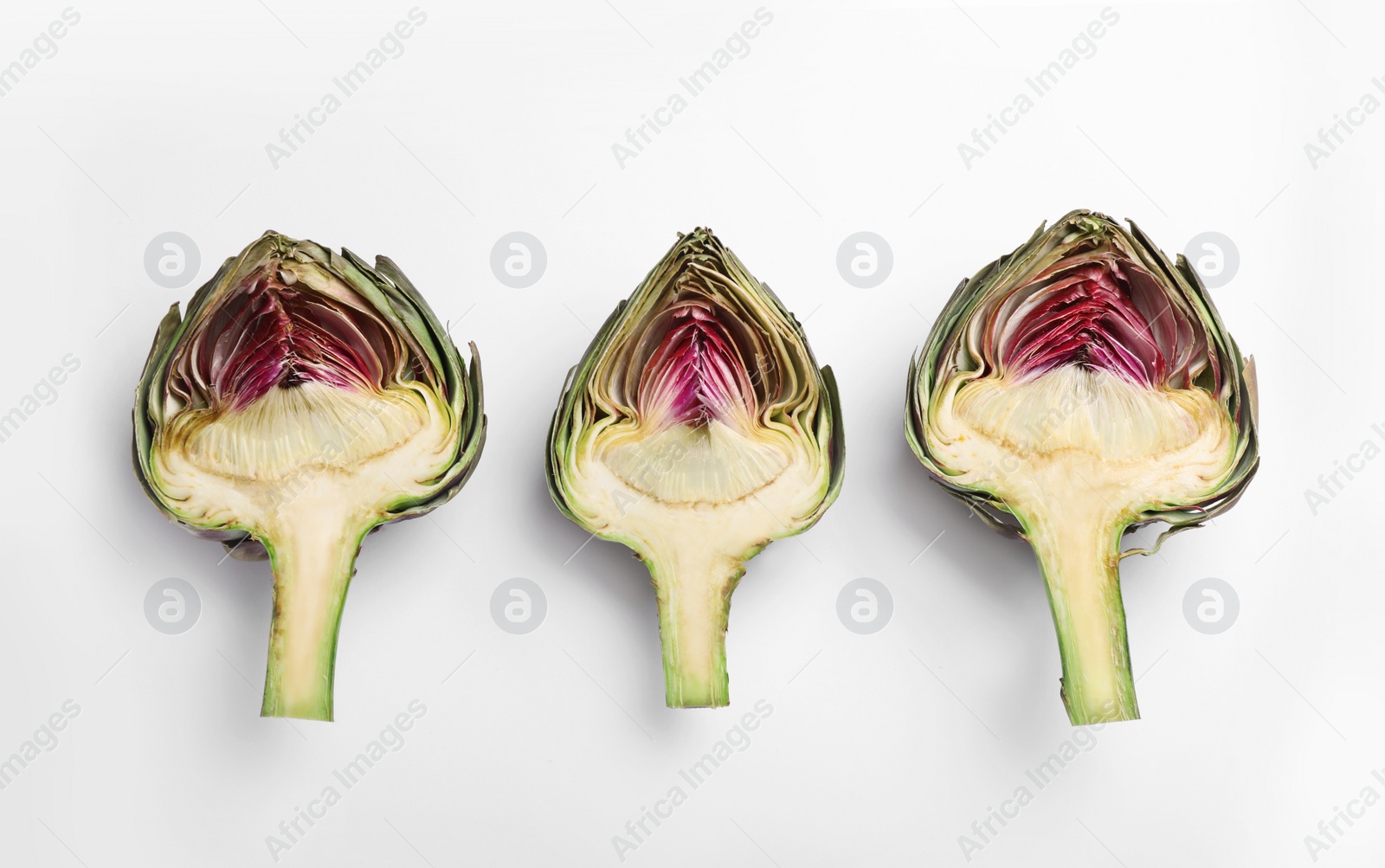 Photo of Cut fresh raw artichokes on white background, flat lay