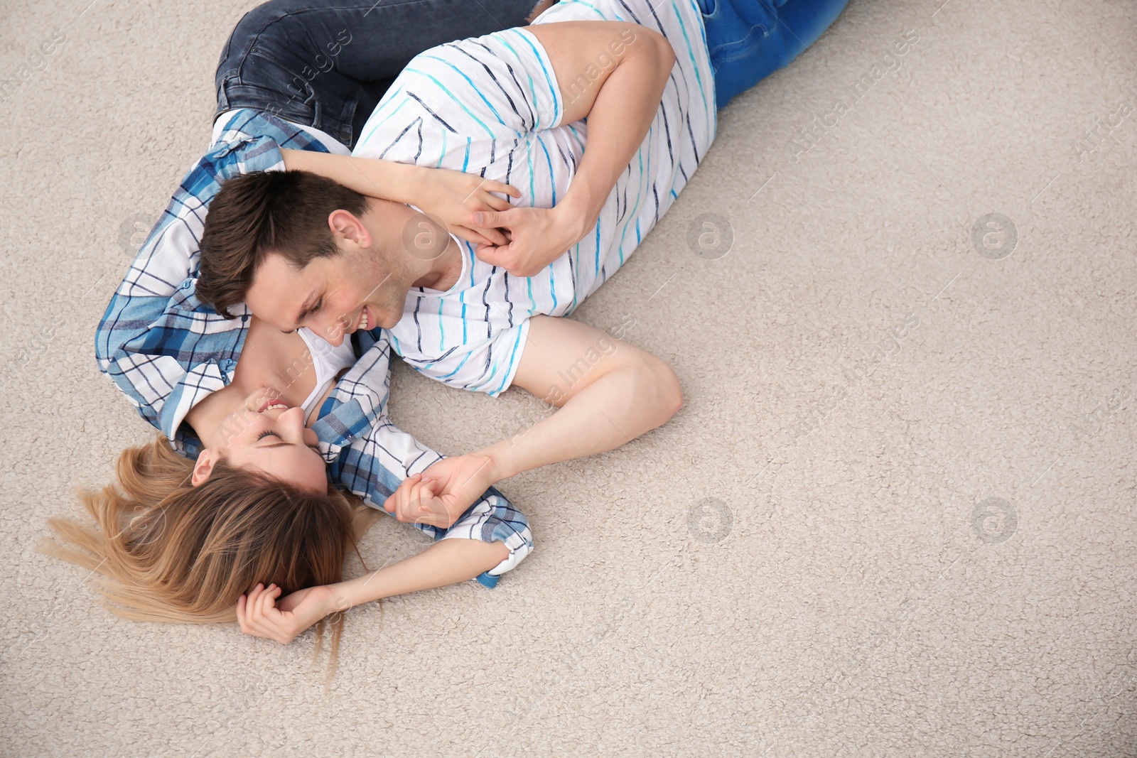 Photo of Lovely young couple lying on cozy carpet at home