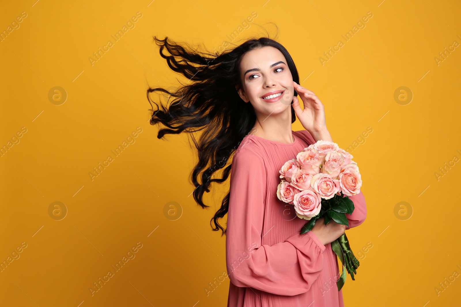 Photo of Portrait of smiling woman with beautiful bouquet on orange background. Space for text