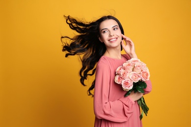 Portrait of smiling woman with beautiful bouquet on orange background. Space for text