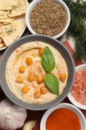 Photo of Delicious creamy hummus with chickpeas and different ingredients on wooden table, flat lay