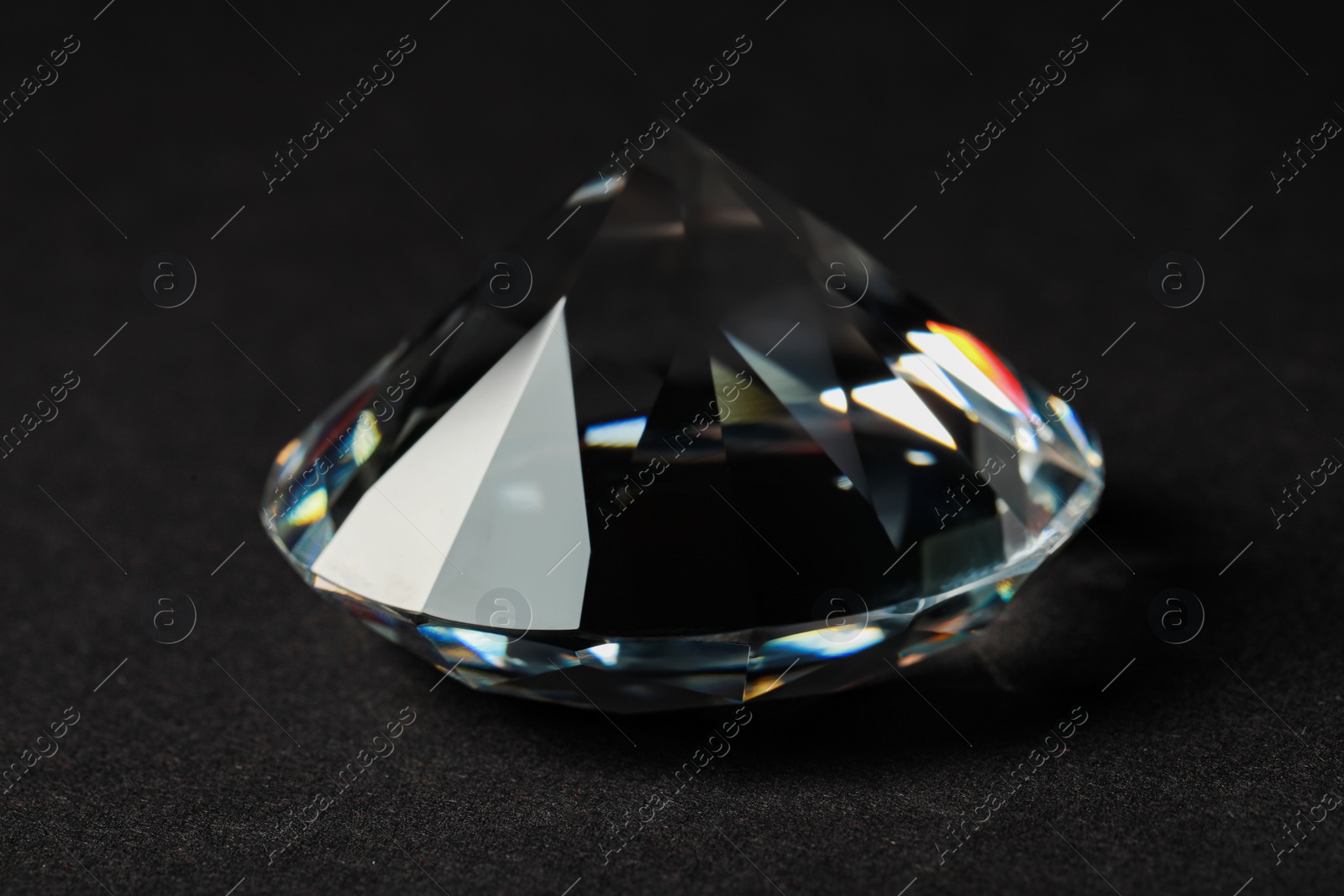 Photo of Beautiful dazzling diamond on dark background, closeup. Precious gemstone