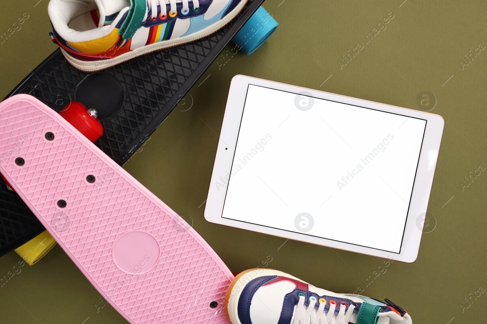 Photo of Modern tablet, skateboards and shoes on olive background, flat lay. Space for text