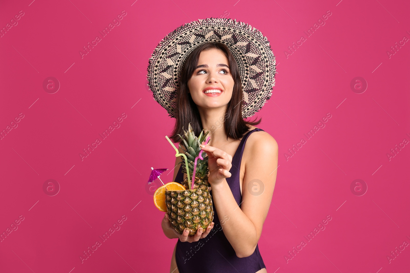 Photo of Beautiful woman in stylish swimsuit holding tropical cocktail on pink background