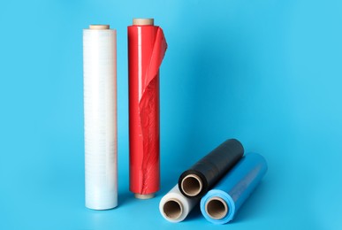 Photo of Rolls of different plastic stretch wrap on light blue background. Space for text