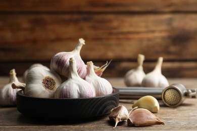 Fresh organic garlic in bowl on wooden table