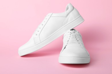 Photo of Pair of stylish white sneakers on pink background