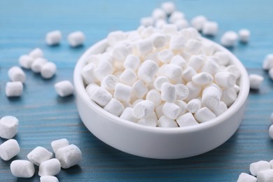 Bowl with delicious marshmallows on light blue wooden table, closeup