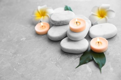 Composition with spa stones, flowers and candles on grey marble background. Space for text