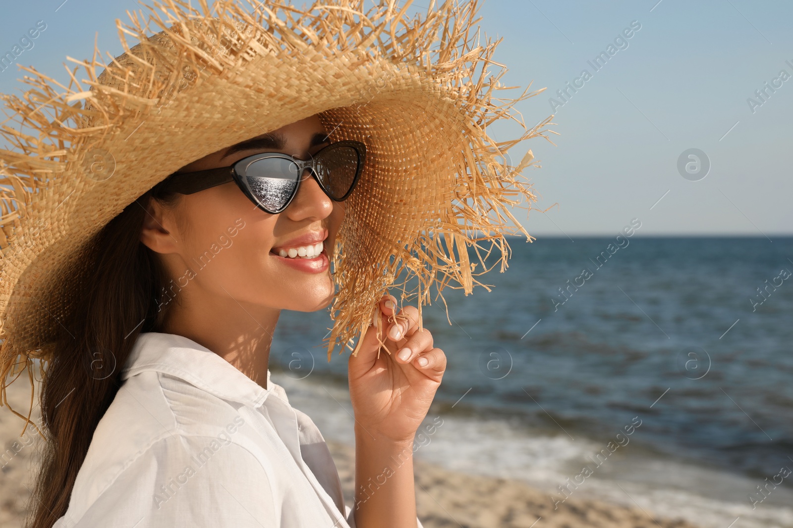 Photo of Young woman with sunglasses and hat at beach. Sun protection care
