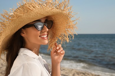 Photo of Young woman with sunglasses and hat at beach. Sun protection care