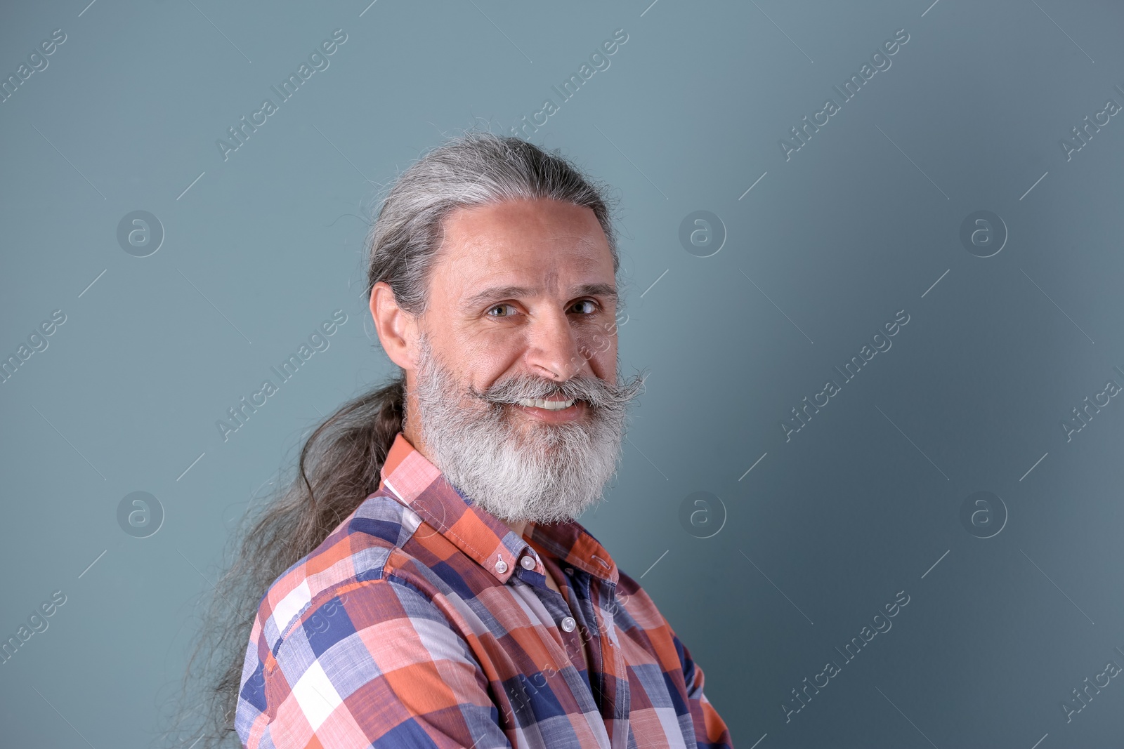 Photo of Handsome bearded mature man on color background