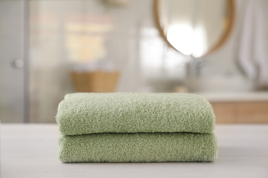 Photo of Stack of clean towels on white wooden table in bathroom