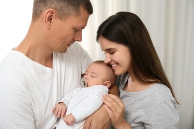 Photo of Happy family with their cute sleeping baby indoors