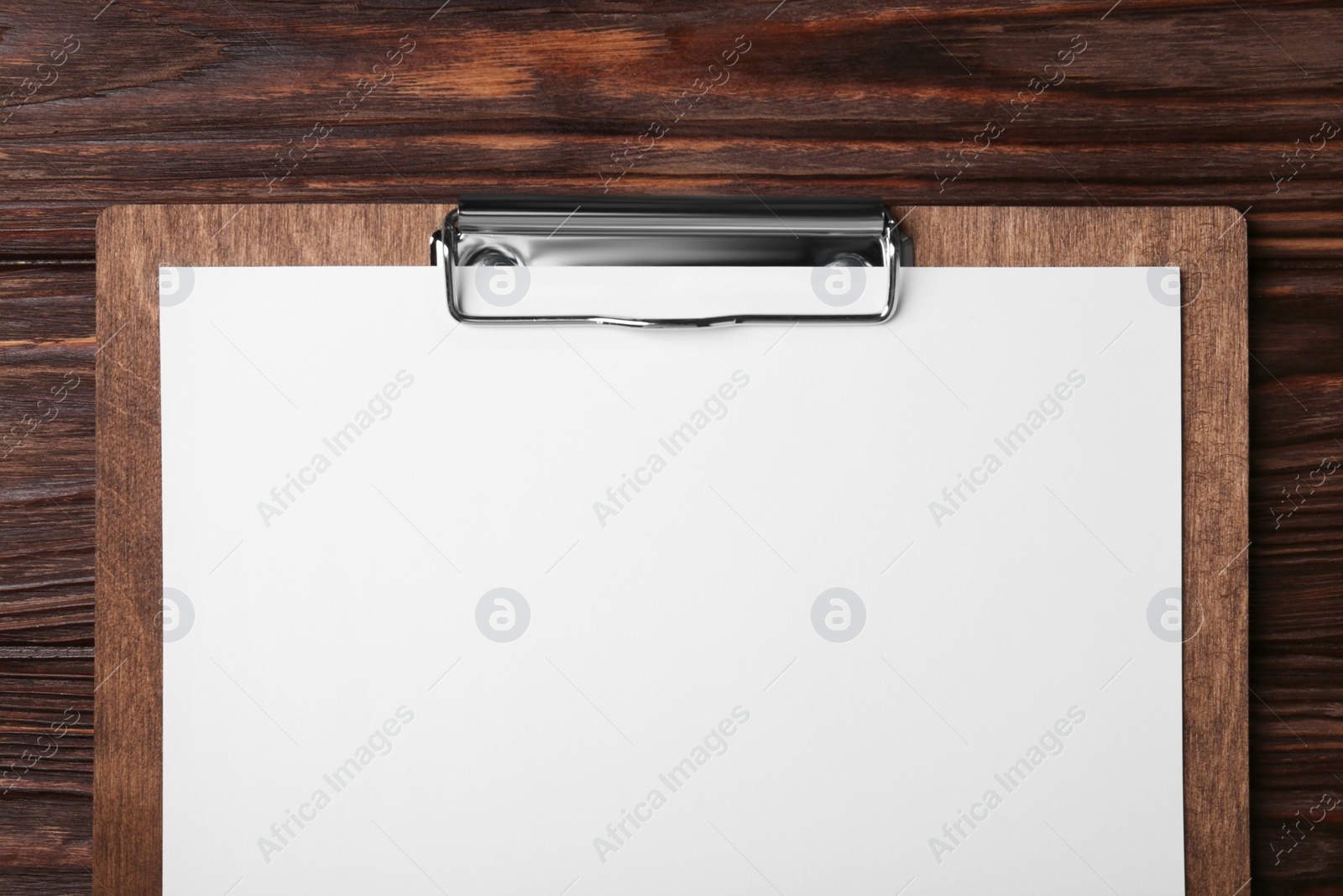 Photo of New clipboard with sheet of blank paper on wooden table, top view