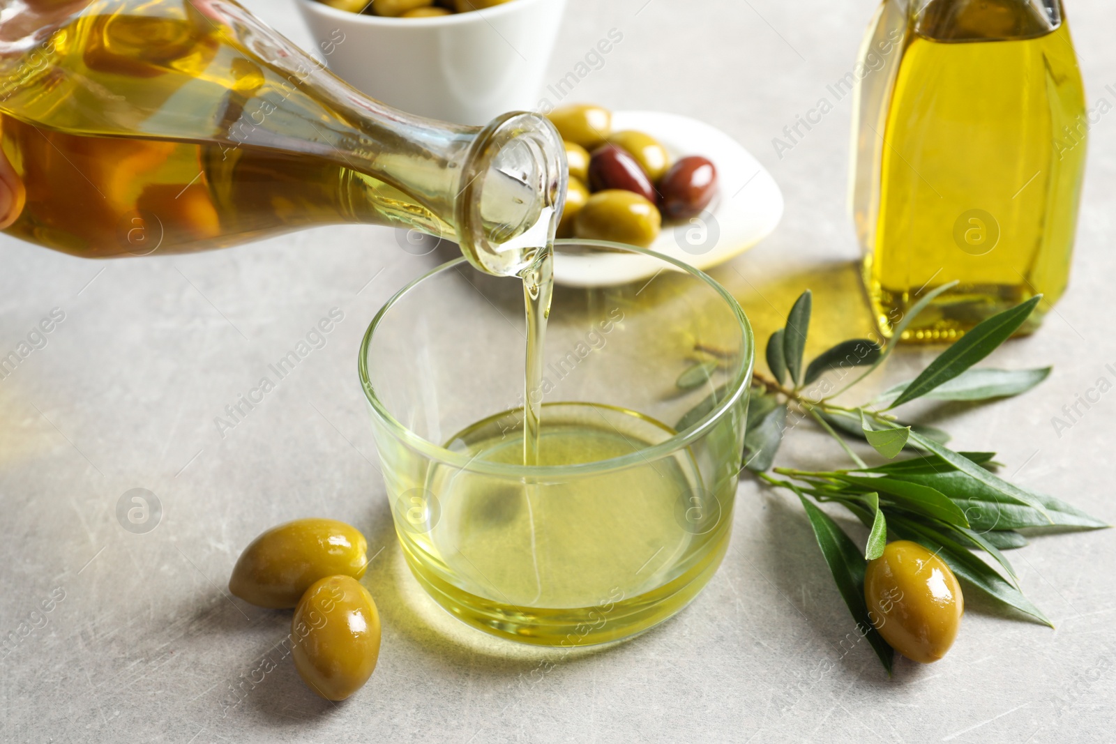 Photo of Pouring fresh olive oil into glass on table