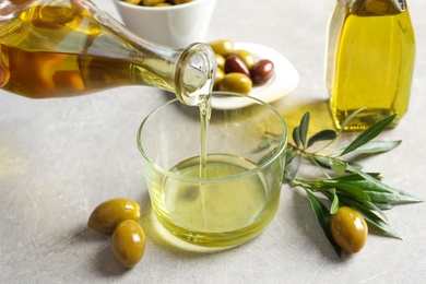 Photo of Pouring fresh olive oil into glass on table