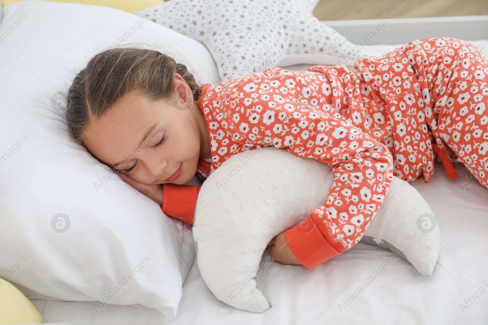 Photo of Cute girl in pajamas sleeping with moon shaped pillow at home