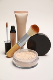 Loose face powder and other makeup products on light background, closeup