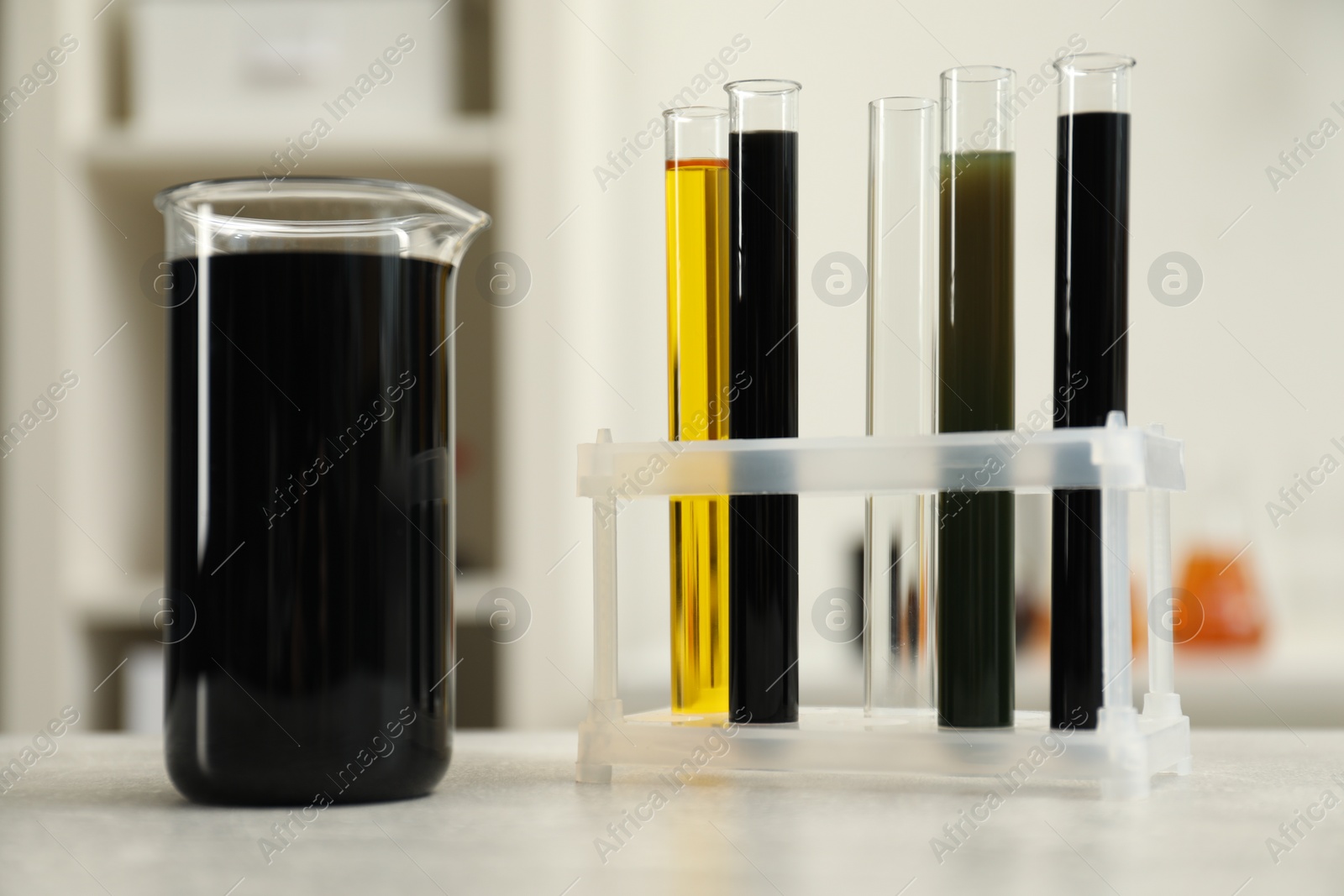 Photo of Laboratory glassware with different types of crude oil on light grey table