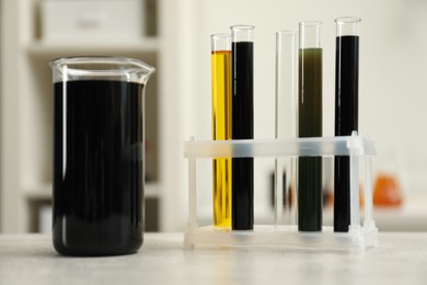 Laboratory glassware with different types of crude oil on light grey table