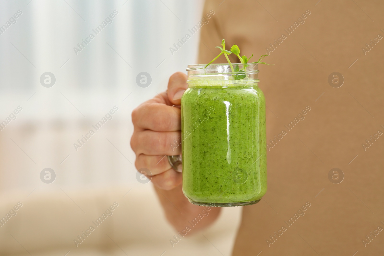 Photo of Man holding mason jar with delicious smoothie indoors, closeup. Space for text