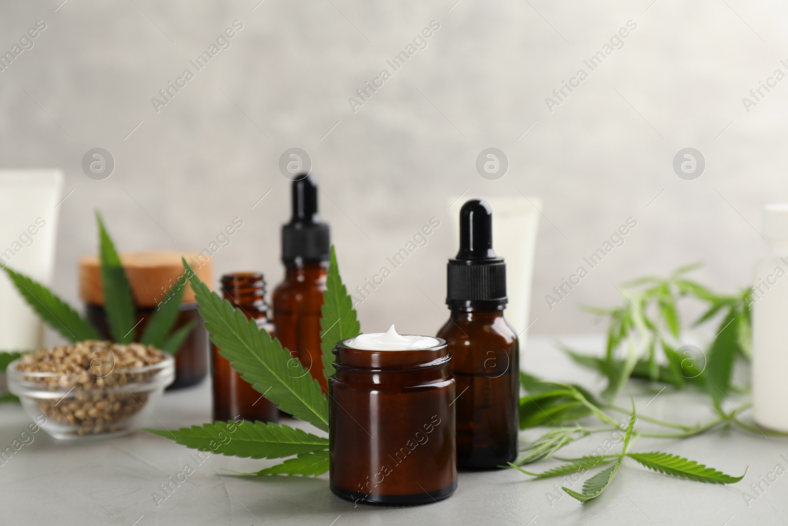 Photo of Composition with CBD oil, THC tincture and hemp leaves on light stone table