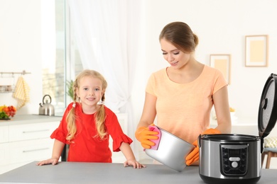 Photo of Mother and daughter cleaning modern multi cooker in kitchen