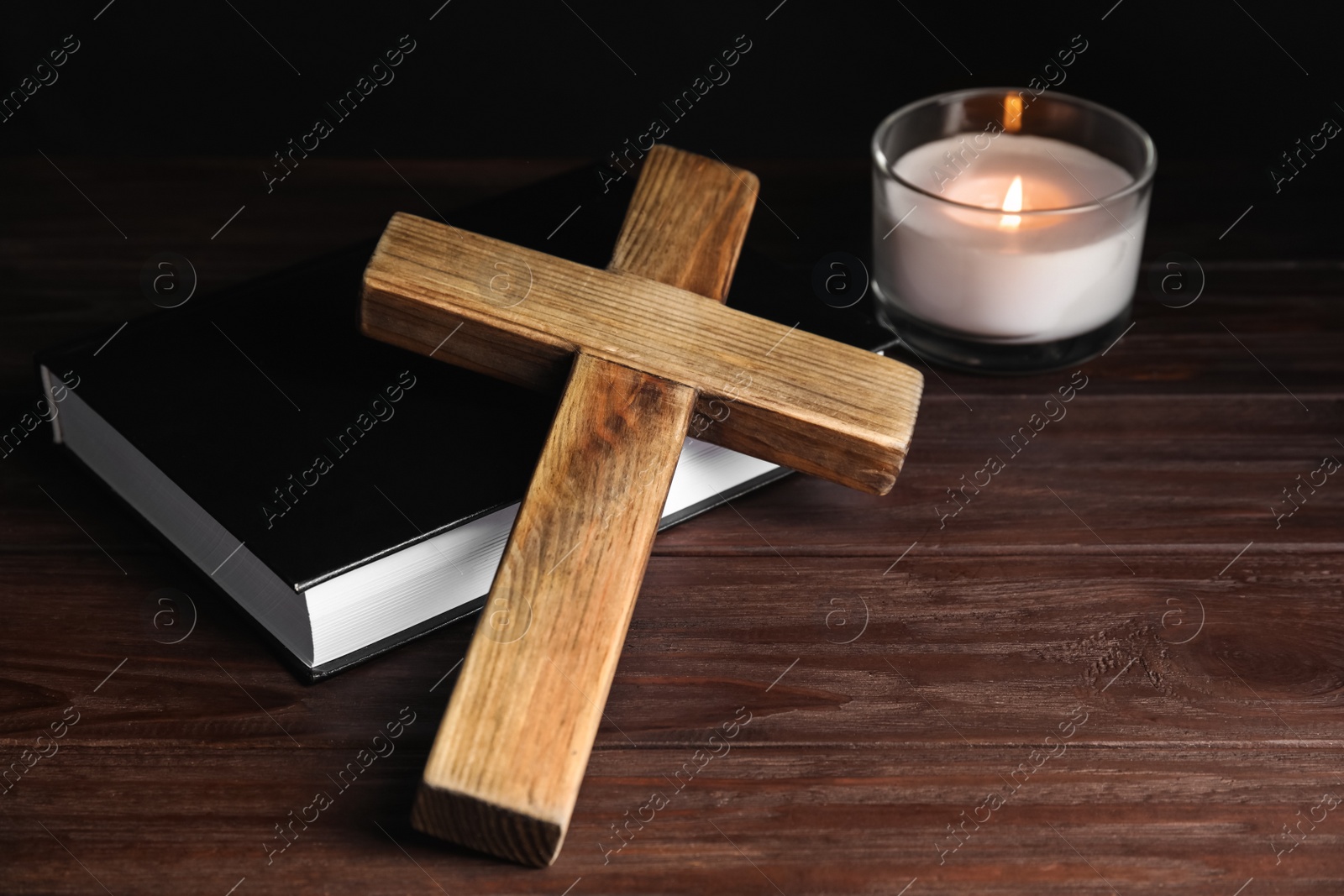 Photo of Cross, Bible and burning candle on wooden background, closeup. Christian religion