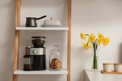 Modern coffee grinder on shelving unit in kitchen