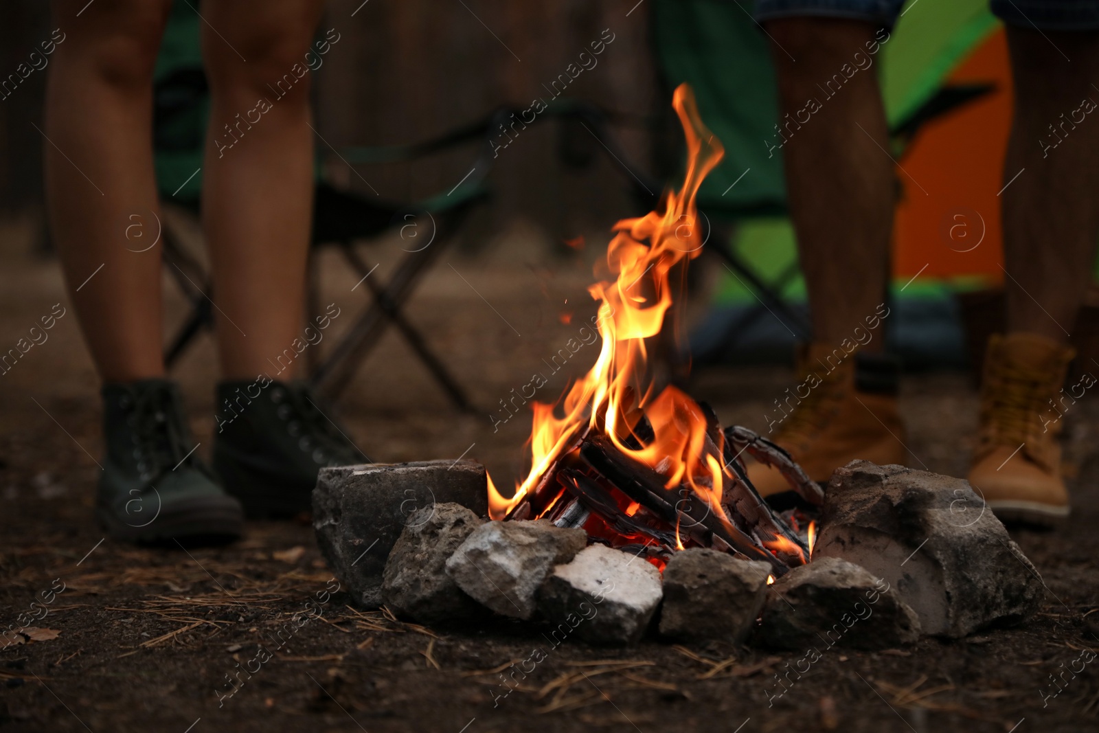 Photo of People near bonfire with burning firewood outdoors, closeup