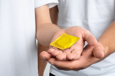 Photo of Young gay couple holding condom together, closeup