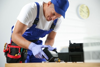 Professional repairman fixing modern printer in office