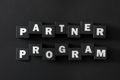 Image of Words Partner Program made of cubes with letters on black background, top view