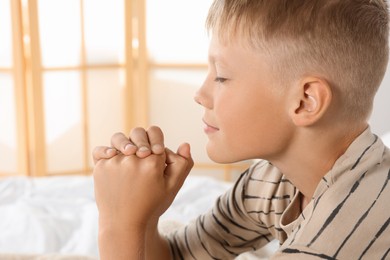 Photo of Boy with clasped hands praying at home