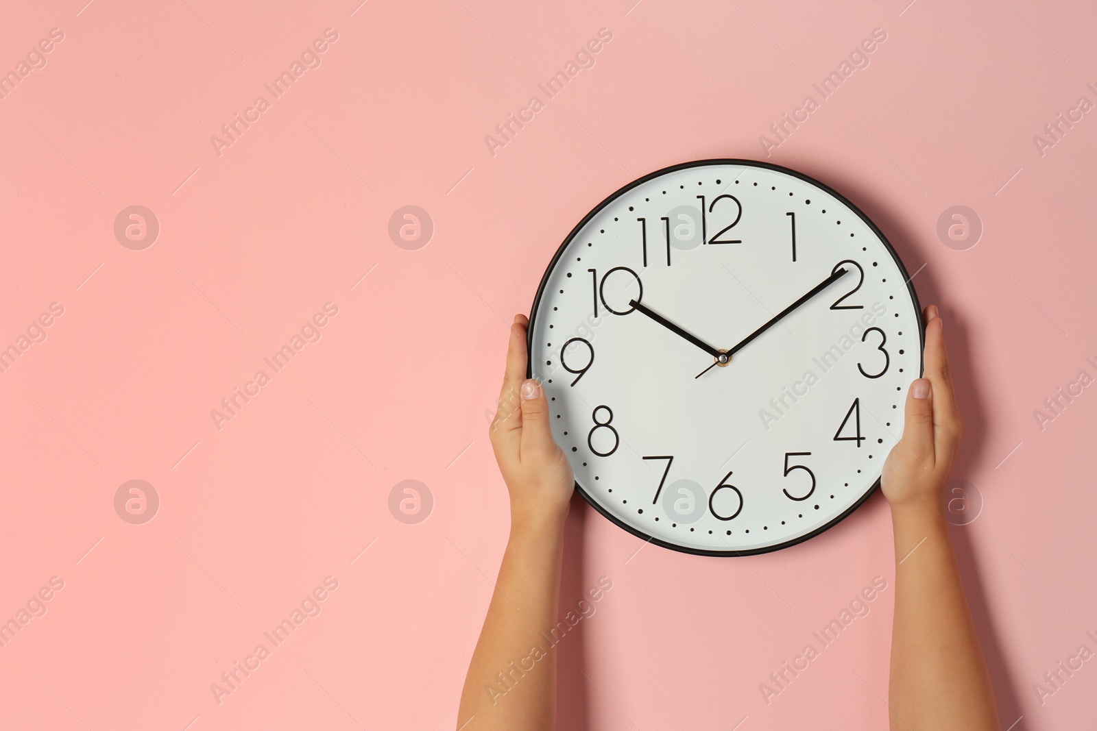 Photo of Woman touching clock on color wall, space for text. Time management