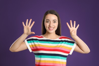 Photo of Woman showing number nine with her hands on purple background