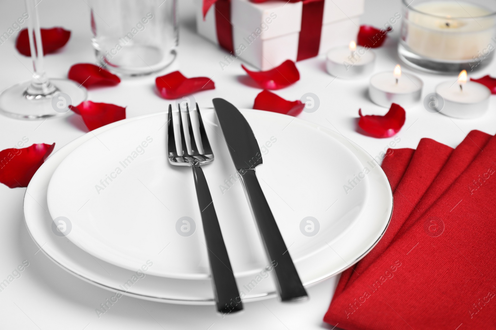 Photo of Beautiful table setting with rose petals on white table, closeup. Romantic dinner