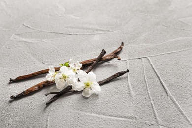 Vanilla sticks and flowers on light background