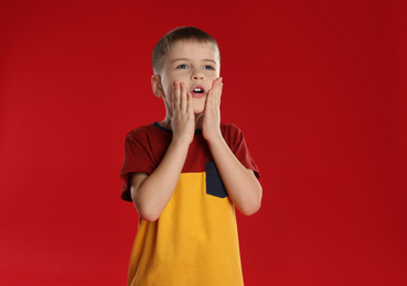 Photo of Portrait of surprised little boy on red background