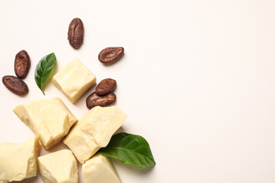 Photo of Organic cocoa butter and beans on beige background, flat lay. Space for text