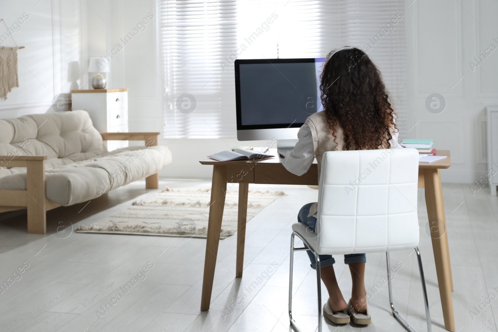 Photo of African American woman with headphones studying at home, back view. Distance learning