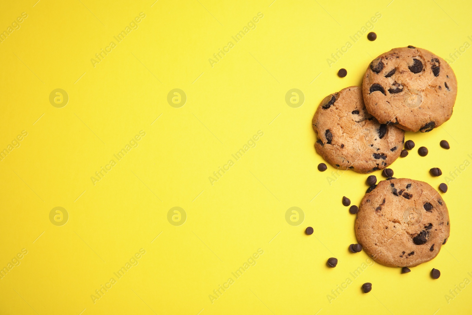 Photo of Delicious chocolate chip cookies on color background, flat lay. Space for text