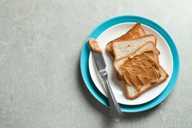 Photo of Plate with toast bread and peanut butter on table, top view