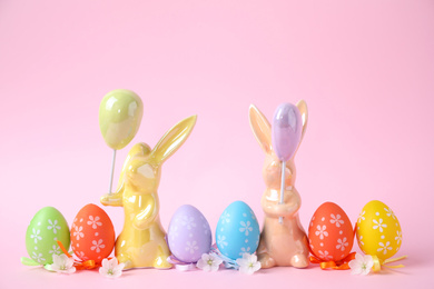 Photo of Easter bunnies and painted eggs on pink background