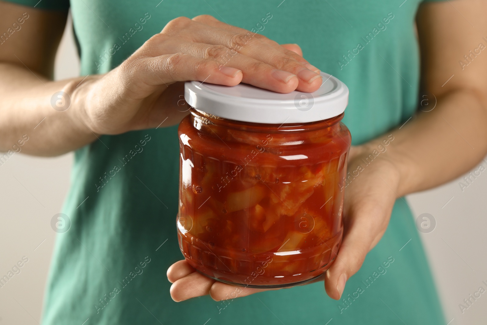 Photo of Woman holding jar of canned lecho, closeup