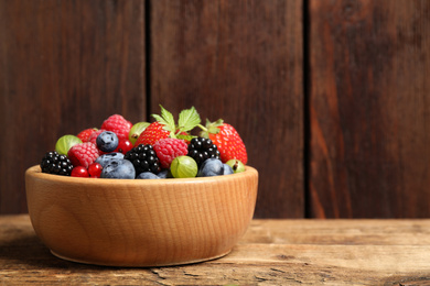 Photo of Mix of ripe berries on wooden table. Space for text